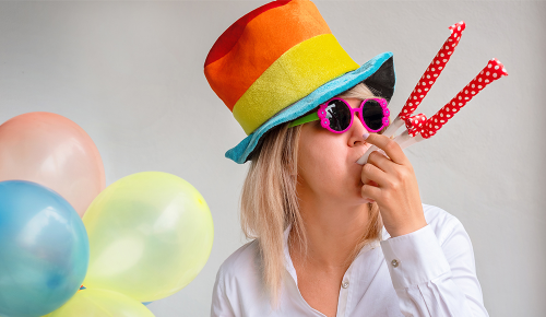 Eine Frau mit einem lustigen Faschingshut und einer Brille