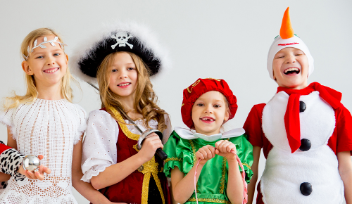 Vier unterschiedliche verkleidete Kinder lachen in die Kamera