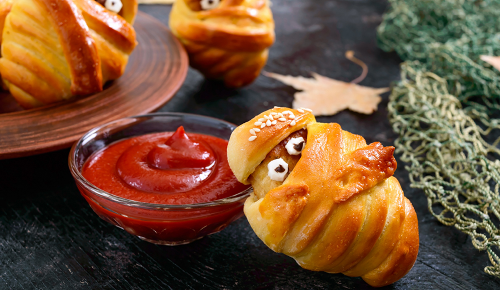 Eine Teigrolle mit Augen neben einem Schälchen Ketchup