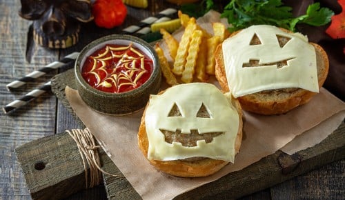 Eine Käsescheibe mit einem gruseligen Gesicht auf einem Burgerfleisch