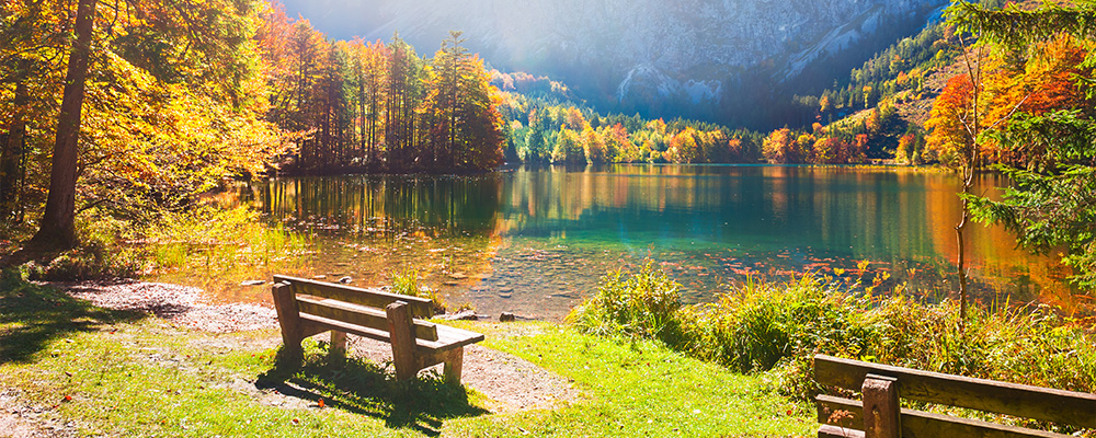 Eine Holzbank im Sonnenschein an einem Bergsee