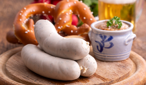 Frische Weißwürste, Brezeln und Weißbier auf einem Tisch