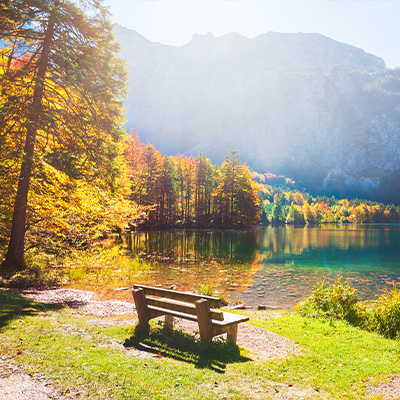 Eine Holzbank im Sonnenschein an einem Bergsee