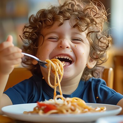Glückliches Kind, das eine frisch zubereitete gesunde Mahlzeit mit Nudeln isst