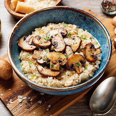 Risotto mit braunen Champignons auf Holzhintergrund. 