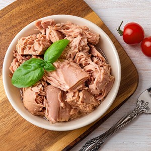Draufsicht auf Thunfisch aus der Dose in einer Schüssel, Gabel und rote Kirschtomaten 