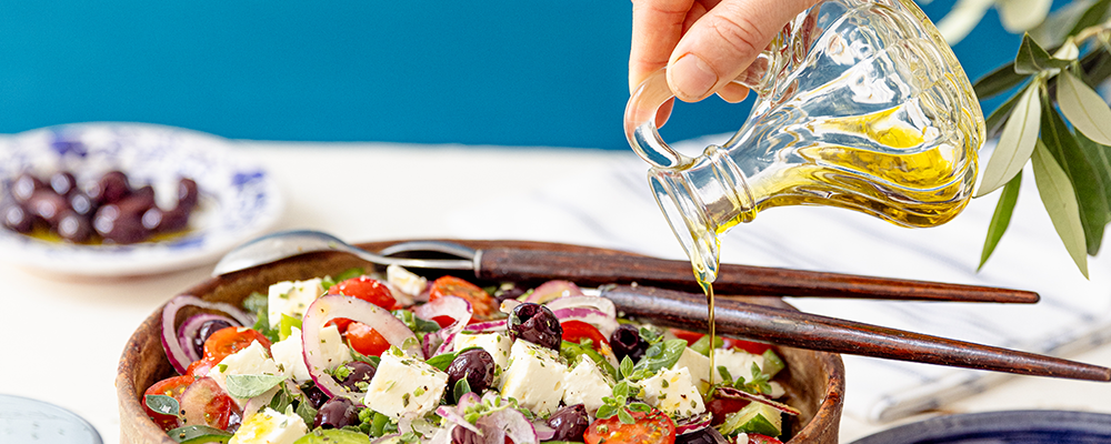 Olivenöl wird in einen griechischen Salat von der SPAR Mahlzeit! gegossen