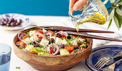 Olivenöl wird in einen griechischen Salat von der SPAR Mahlzeit! gegossen