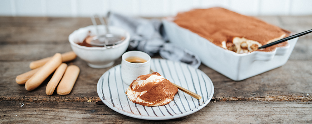 Ein Tiramisu in einer Schale und ein Stück Tiramisu auf einem Teller - Rezeptbild aus der SPAR Mahlzeit