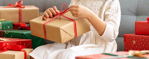 Ein Kind beim Auspacken von Geschenken auf einem Sofa