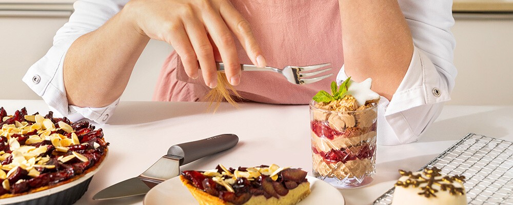 Patissiere Lisa Krispl sitzt an einem Tisch mit vielen leckeren Pattisiere-Gerichten