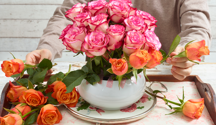 Eine Vase voller oranger und rosafarbener Rosen