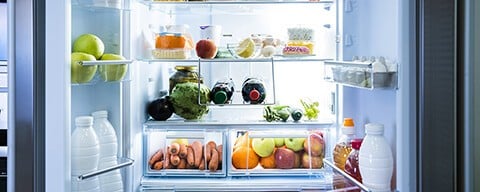 Blick in einen geöffneten Kühlschrank mit verschiedenen Lebensmitteln