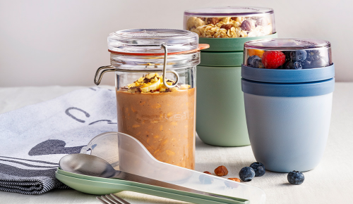 Drei Dosen mit Overnight Oats in Kaffeebechern aus Glas