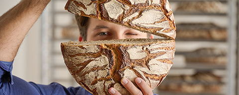 Ein Mann mit einem Laib Brot in den Händen lächelt