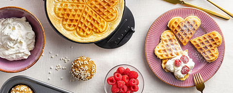 Frisch gemachte Waffeln neben einer Schale Beeren auf einem Tisch