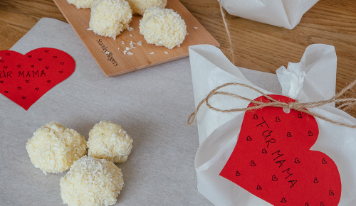 Selbstgemachte Kokosbällchen und ausgeschnittene Papierherzen