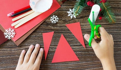 Ein Kind hat rotes Papier in mehrere Dreiecke geschnitten