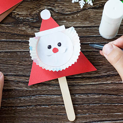 Ein Kind hat einen Nikolaus mit Gesicht aus Papier gebastelt