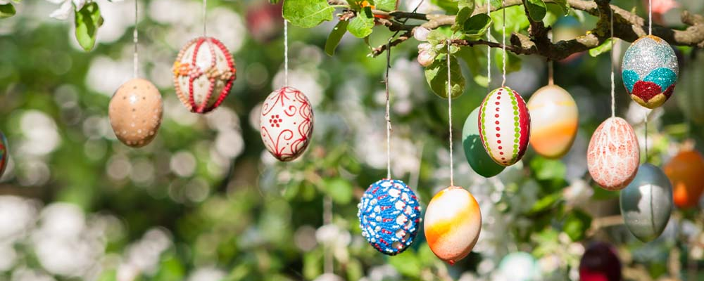 Viele bunte Ostereier hängen an einem blühenden Busch