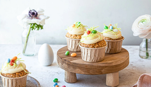 Vier Ostermuffins dekoriert mit Frosting und Zucker-Eiern 