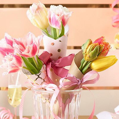 Bunte Tulpen verpackt mit bunten Schleifen und Geschenkpapier in einer Vase