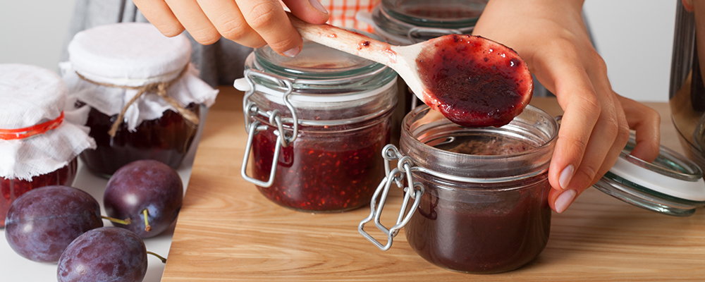 Eine Person füllt selbstgemachte Marmelade in Gläser