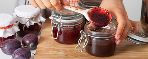 Eine Person füllt selbstgemachte Marmelade in Gläser