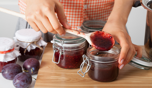 Eine Person füllt selbstgemachte Marmelade in Gläser