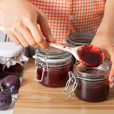 Eine Person füllt selbstgemachte Marmelade in Gläser