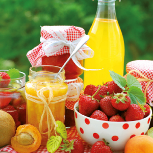 Verschiedene Beeren, ein Glas mit Marmelade und eine Glasflasche