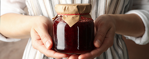 Eine Person hält ein Glas Marmelade in den Händen