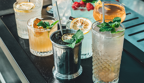 Mehrere verschiedene Cocktails in Gläsern auf einem Bartresen