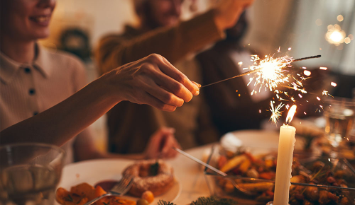 Mehrere Personen mit Wunderkerzen an einem festlichen Tisch
