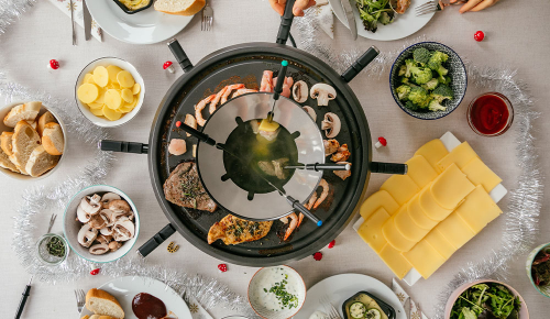 Ein großer Raclette-Grill und verschiedene Zutaten auf einem Tisch