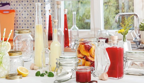 Verschiedene Gefäße mit Säften, Marmeladen und Obst zum Einkochen