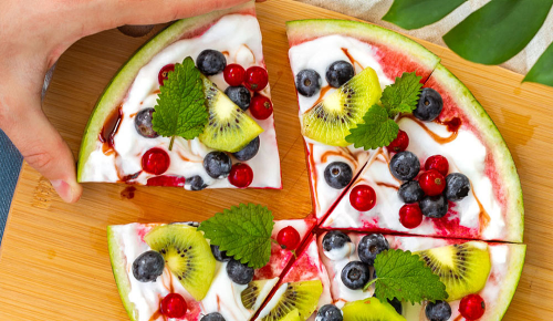 Eine Pizza aus Wassermelone belegt mit Jogurt, Obst und Beeren