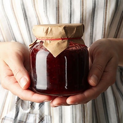 Eine Person hält ein Glas Marmelade in den Händen