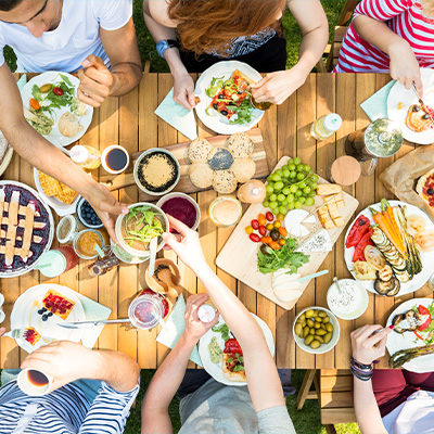 Viele Personen und viele verschiedene Gerichte auf einem Picknicktisch