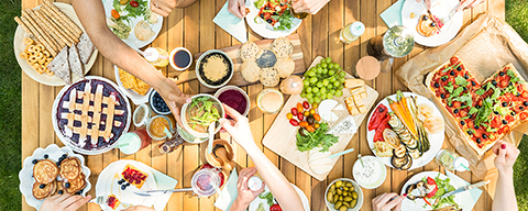 Viele Personen an einem Picknicktisch mit vielen verschiedenen Gerichten