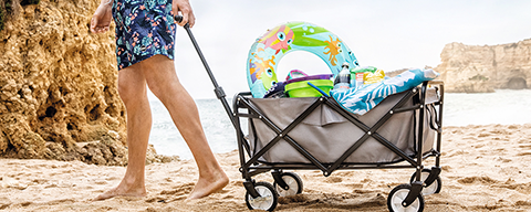 Eine Person spaziert mit einem Strandwagen über einen Strand