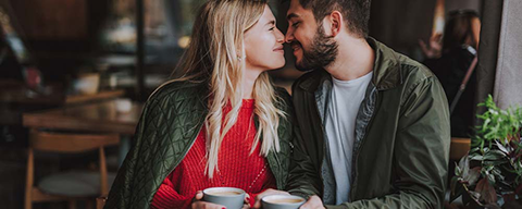 Ein Pärchen sitzt gemeinsam beim Kaffeetrinken in einem Café