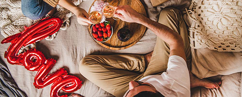 Ein Mann und Frau sitzen gemeinsam bei einem Frühstück im Bett