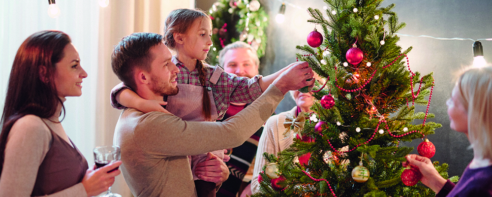 Zwei Erwachsene und ein Kind beim Anschauen eines Christbaumes