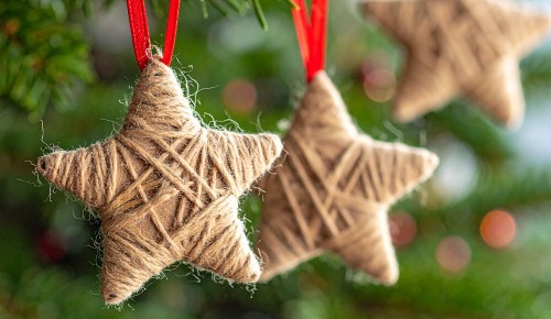 Selbst gebastelter Christbaumschmuck aus Karton und Schnur in Form von Sternen hängt am Christbaum