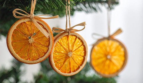 Selbst gebastelter Christbaumschmuck aus getrockneten Orangenscheiben hängt am Christbaum