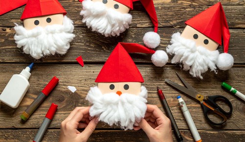 Selbst gebastelter Weihnachtsschmuck aus Papier und Wolle in Form von Weohncahtsmännern