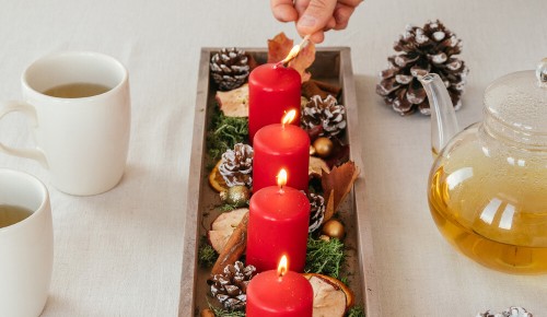 Ein Adventsgedeck mit roten Kerzen, Tannenzweigen und Deko