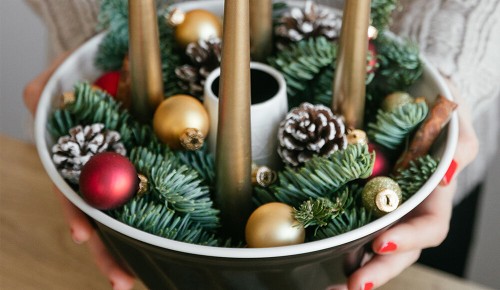 Ein Adventkranz in einer Schale mit langen goldenen Kerzen