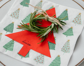 Eine Tannenbaum-Serviette, ein roter Papiertannenbaum und ein Rosmarin-Kranz